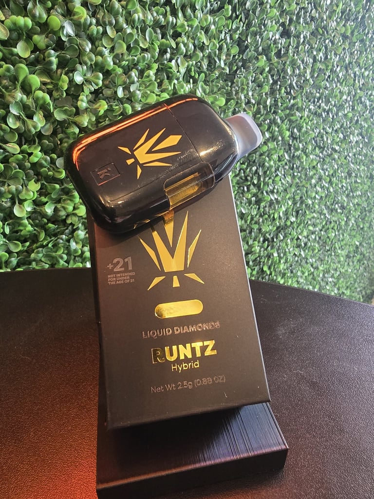 Black and gold Runtz Hybrid liquid diamonds vape cartridge and packaging displayed on green and brown background