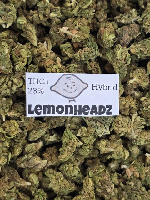 Close-up of dried cannabis buds labeled Lemonheadz Hybrid strain with 28% THCa content and smiley face icon
