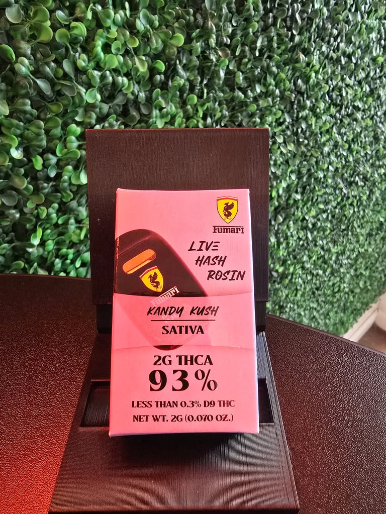 Pink Zumari cannabis product box displaying Lips Hash Rosin Kandy Kush Sativa with 93% THCA on brown wooden block against green plant background