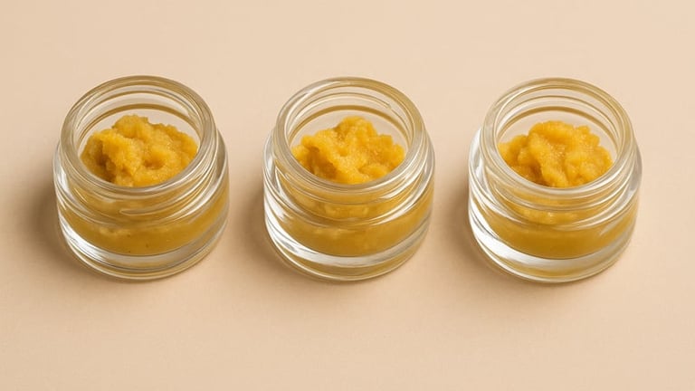 Three glass jars filled with golden concentrate or oil on a beige background