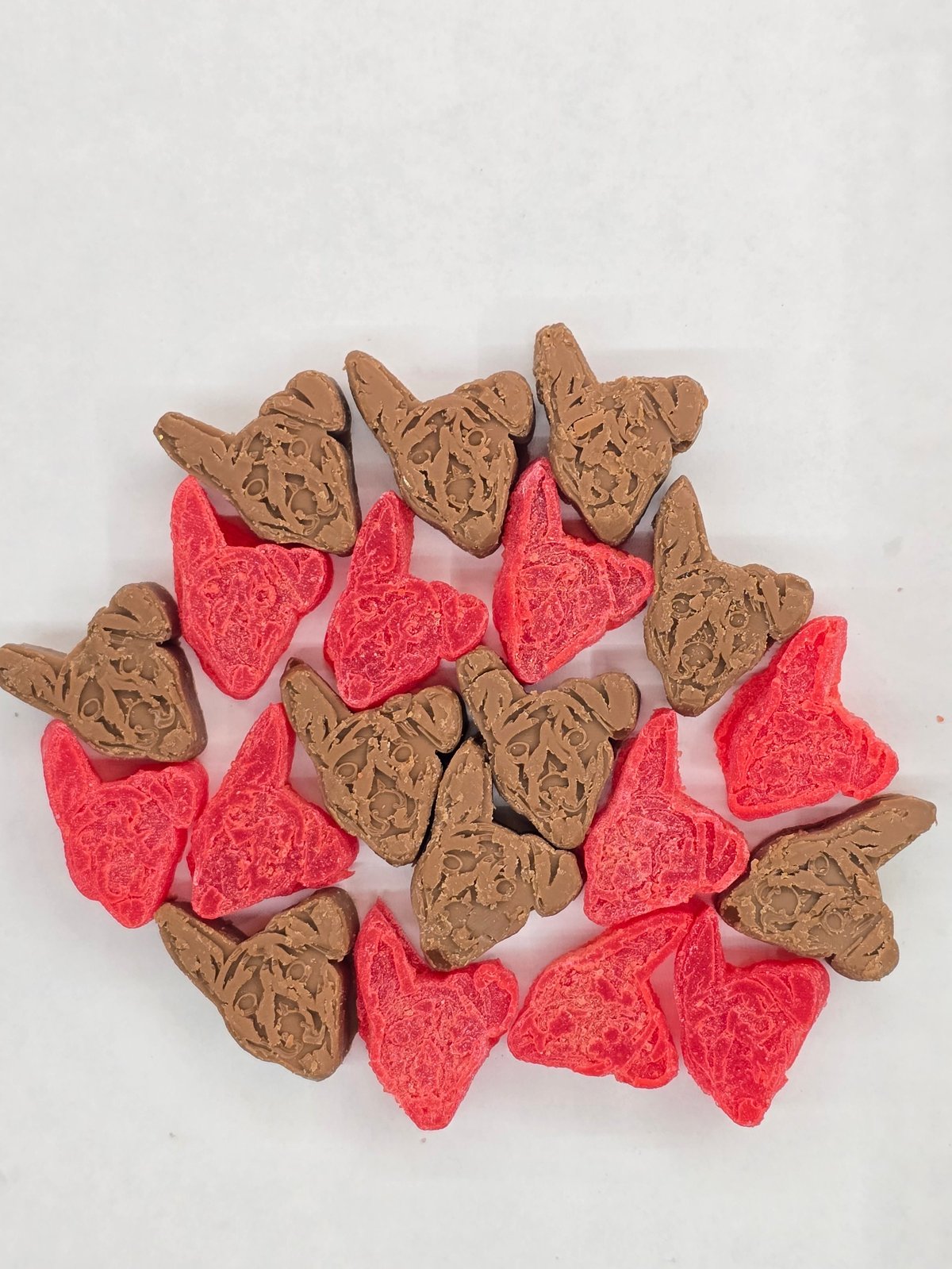 Circular arrangement of alternating brown textured heart-shaped cookies and pink sparkly heart-shaped candies on white background