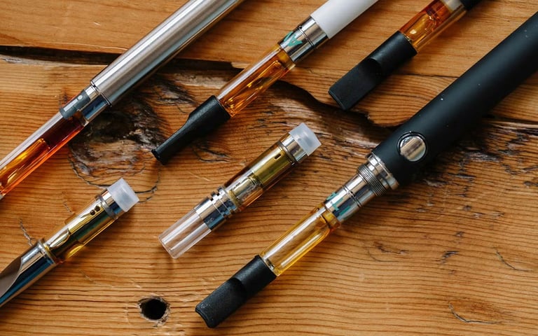 Vaping pens and atomizers arranged on a wooden surface, showing various styles and components