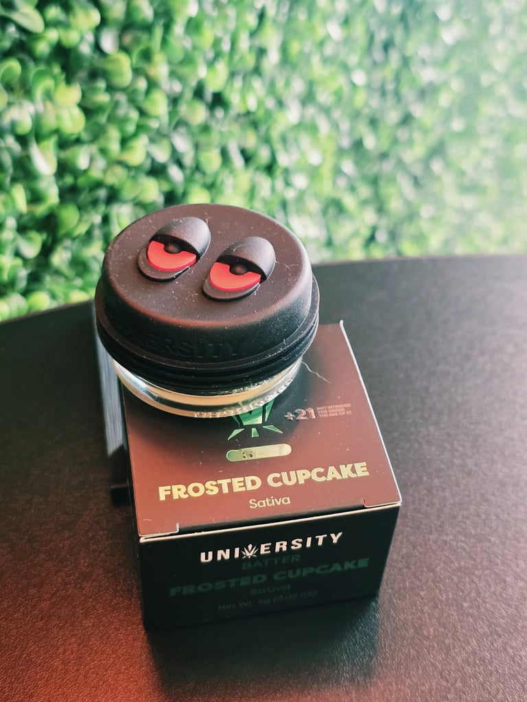 Frosted Cupcake cannabis product with a round chocolate container featuring red eyes, displayed on branded packaging