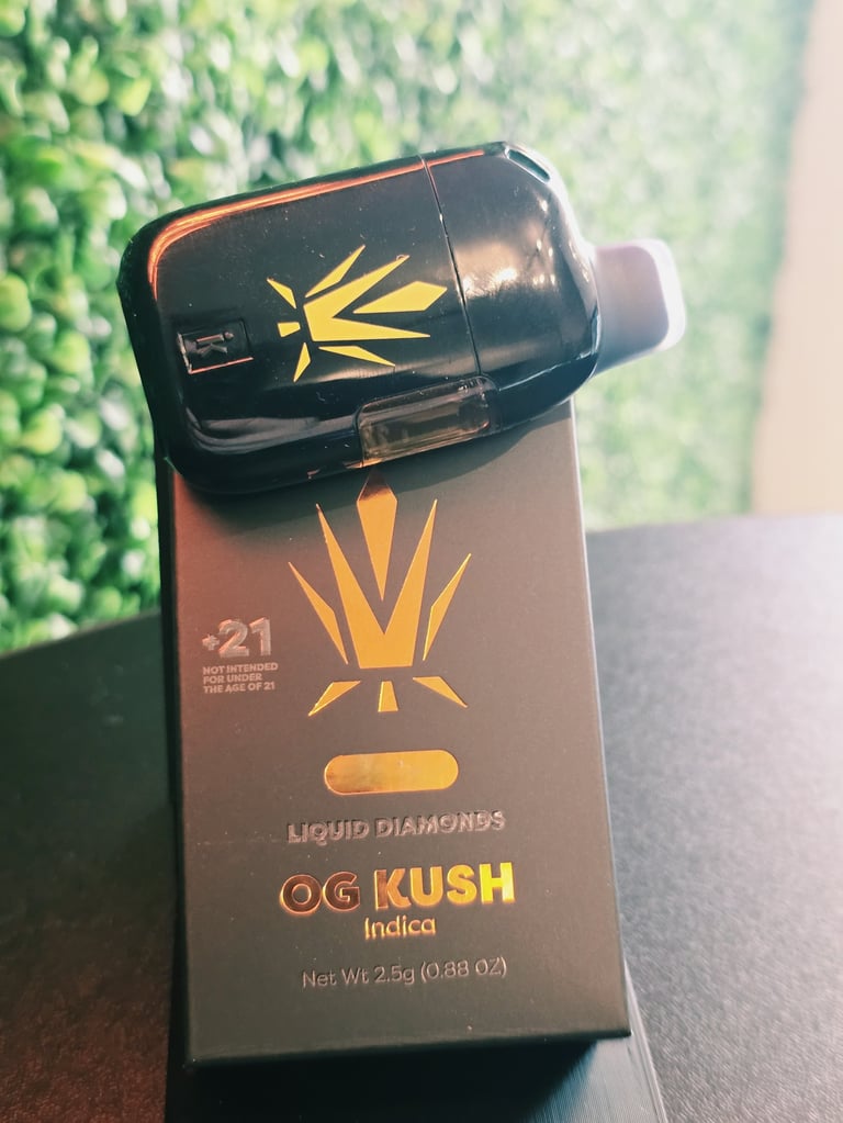 Black vial of OG Kush Indica cannabis product with gold sun logo on brown box label, 25g net weight
