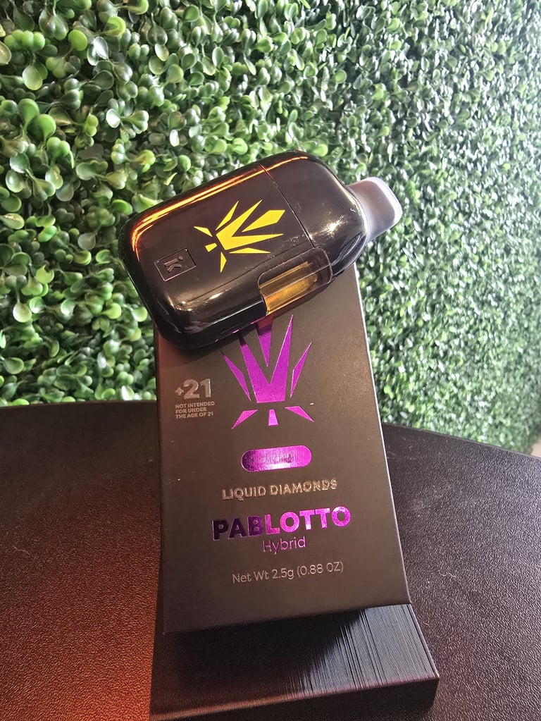 Black package of Dabotto hybrid liquid diamonds with purple crown logo and yellow striped vape cartridge on artificial grass background